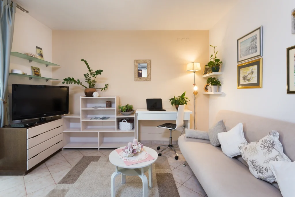 Svijetli dnevni boravak s trosjedom, TV-om i radnim kutkom u apartmanu Arca Strožanac