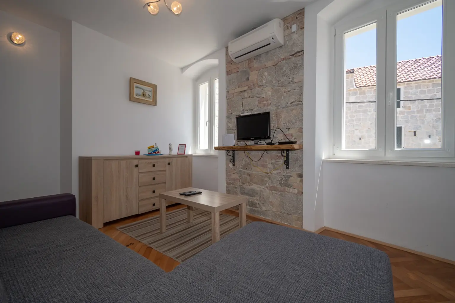 Dnevni boravak s kaučem i komodom uz kameni zid, apartman Kira Split